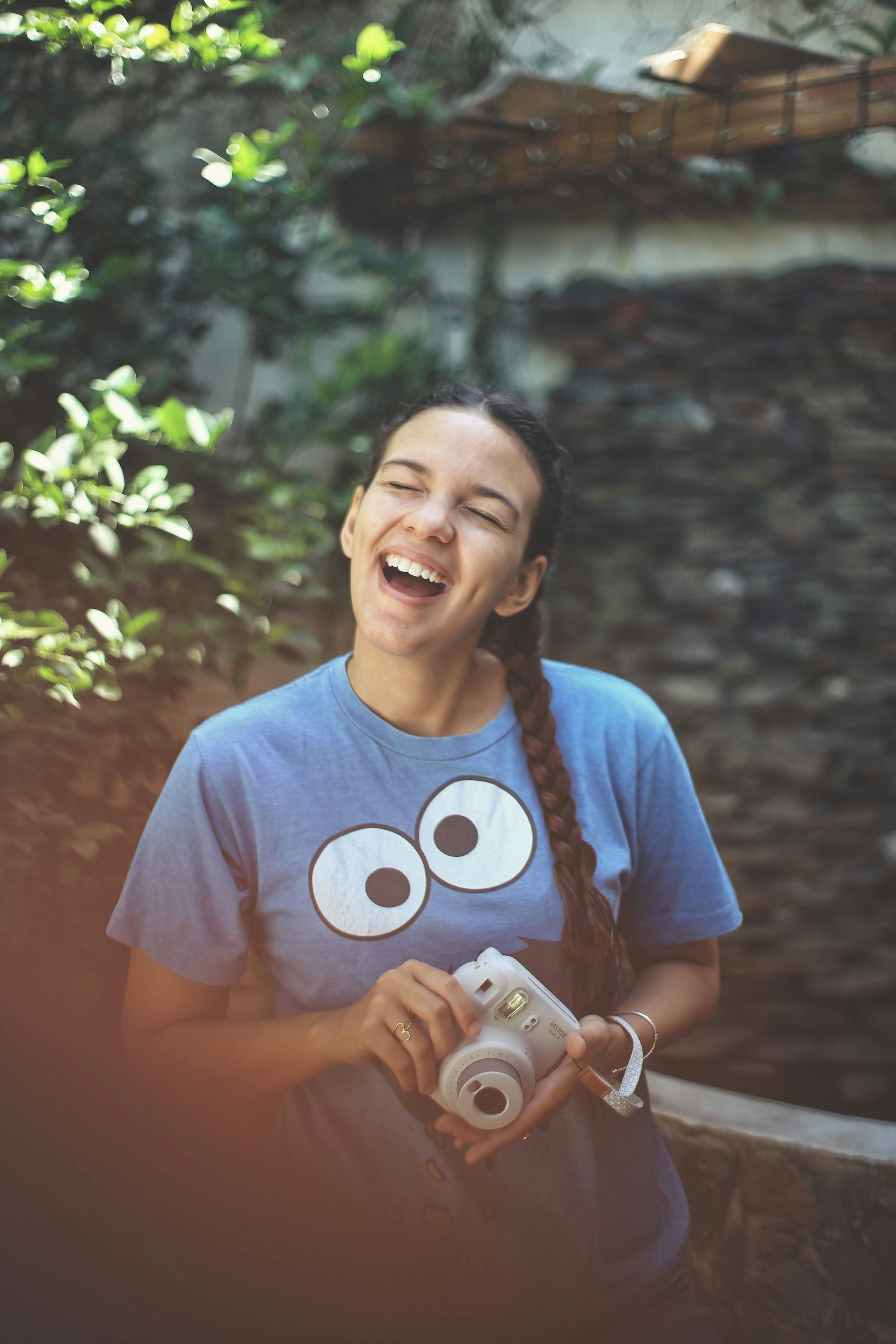 woman in blue crew neck t-shirt holding white camera